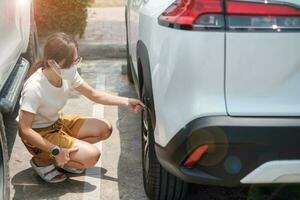 mujer conductora inflando a mano los neumáticos del vehículo, quitando la tapa de nitrógeno de la válvula del neumático para comprobar la presión del aire y llenando el aire en la rueda del coche en la gasolinera. autoservicio, mantenimiento y seguridad foto