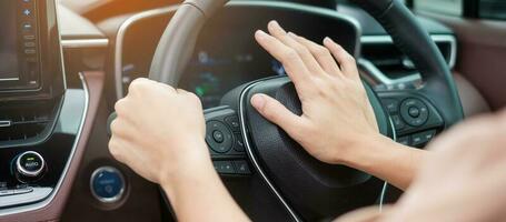 woman driver honking a car during driving on traffic road, hand controlling steering wheel in vehicle. Journey, trip and safety Transportation concepts photo