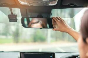 mujer conductora ajustando el espejo retrovisor de un coche. conceptos de transporte de viaje, viaje y seguridad foto