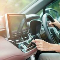 Woman hand adjusting temperature the air flowing during driving car on the road, air conditioner cooling system inside the car. Adjust, temperature and transport concept photo