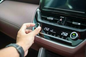 man hand adjusting temperature the air flowing during driving car on the road, air conditioner cooling system inside the car. Adjust, temperature and transport concept photo