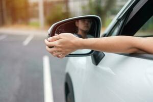 mujer conductora ajustando el espejo retrovisor de un coche. conceptos de transporte de viaje, viaje y seguridad foto