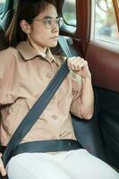 woman driver hand fastening seat belt during sitting inside a car and driving in the road. safety, trip, journey and transport concept photo