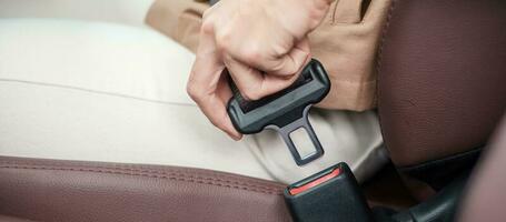 woman driver hand fastening seat belt during sitting inside a car and driving in the road. safety, trip, journey and transport concept photo