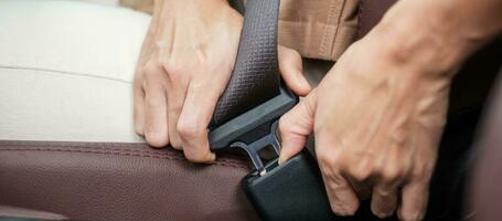 woman driver hand fastening seat belt during sitting inside a car and driving in the road. safety, trip, journey and transport concept photo