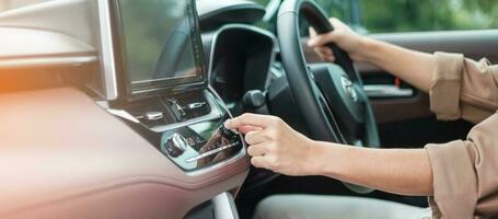 Woman hand adjusting temperature the air flowing during driving car on the road, air conditioner cooling system inside the car. Adjust, temperature and transport concept photo