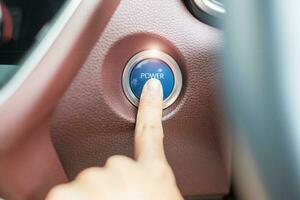 Finger press a car ignition button or START engine inside modern electric automobile. Keyless, change, strategy, vision, innovation and future concept photo