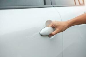 Hand holding smart car handle and opening a door. Transport, travel, service and car rental concept photo