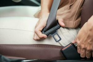 woman driver hand fastening seat belt during sitting inside a car and driving in the road. safety, trip, journey and transport concept photo