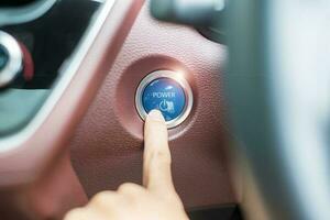 Finger press a car ignition button or START engine inside modern electric automobile. Keyless, change, strategy, vision, innovation and future concept photo