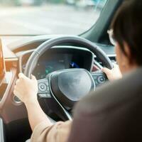 woman driver driving a car on the road, hand controlling steering wheel in electric modern automobile. Journey, trip and safety Transportation concepts photo