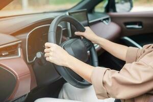 mujer conductora conduciendo un automóvil en la carretera, controlando a mano el volante en un automóvil eléctrico moderno. conceptos de transporte de viaje, viaje y seguridad foto