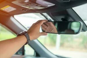 hombre conductor ajustando el espejo retrovisor de un coche. conceptos de transporte de viaje, viaje y seguridad foto