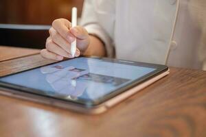 woman using tablet for sms messages, hand holding pencil typing touchscreen mobile phone in cafe or modern office. lifestyle, technology, Social media and network concept photo