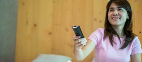 woman hand using remote controller for adjust Smart TV inside the modern room at home photo