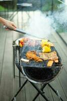 deliciosa carne a la parrilla con humo, barbacoa con verduras al aire libre. barbacoa, fiesta, estilo de vida y concepto de picnic foto