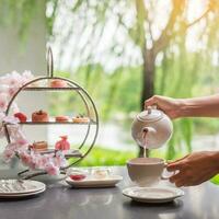 mujer mano torrencial caliente té con tarde té conjunto y rosado postre a lujo hotel foto