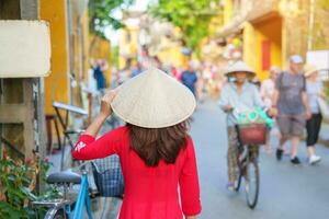 happy woman wearing Ao Dai Vietnamese dress, asian traveler sightseeing at Hoi An ancient town in central Vietnam. landmark and popular for tourist attractions. Vietnam and Southeast travel concept photo