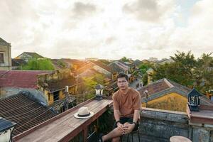 happy traveler traveling at Hoi An ancient town in Vietnam, man sightseeing view at rooftop. landmark and popular for tourist attractions. Vietnam and Southeast Asia travel concept photo