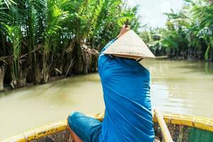 Man rowing a basket boat, along the coconut river forest, a unique Vietnamese at Cam thanh village. Landmark and popular for tourists attractions in Hoi An. Vietnam and Southeast Asia travel concepts photo