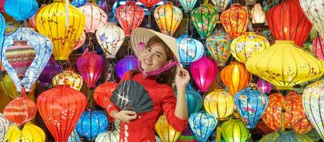 happy woman wearing Ao Dai Vietnamese dress with colorful lanterns, traveler sightseeing at Hoi An ancient town in central Vietnam.landmark for tourist attractions.Vietnam and Southeast travel concept photo