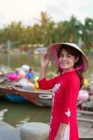 contento mujer vistiendo ao dai vietnamita vestido, viajero visitar Jue bon río y Turismo barco paseo a hoi un antiguo ciudad. punto de referencia para turista atracciones.vietnam y Sureste viaje concepto foto