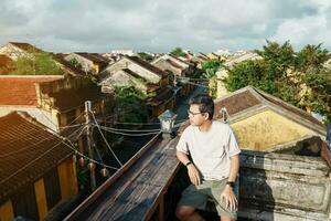 happy traveler traveling at Hoi An ancient town in Vietnam, man sightseeing view at rooftop. landmark and popular for tourist attractions. Vietnam and Southeast Asia travel concept photo