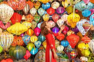 contento mujer vistiendo ao dai vietnamita vestir con vistoso linternas, viajero Turismo a hoi un antiguo pueblo en central vietnam.punto de referencia para turista atracciones.vietnam y Sureste viaje concepto foto