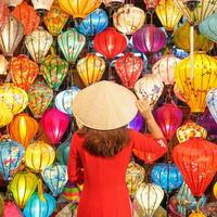 happy woman wearing Ao Dai Vietnamese dress with colorful lanterns, traveler sightseeing at Hoi An ancient town in central Vietnam.landmark for tourist attractions.Vietnam and Southeast travel concept photo