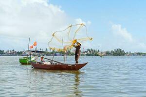 Fisherman Fishing Net on the boat at Cam thanh village. Landmark and popular for tourists attractions in Hoi An. Vietnam and Southeast Asia travel concepts photo