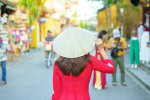 contento mujer vistiendo ao dai vietnamita vestido, asiático viajero Turismo a hoi un antiguo pueblo en central Vietnam. punto de referencia y popular para turista atracciones Vietnam y Sureste viaje concepto foto