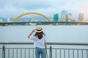 mujer viajero visitando en da nang ciudad. turista Turismo el río ver con continuar puente. punto de referencia y popular para turista atracción. Vietnam y Sureste Asia viaje concepto foto