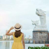 mujer viajero con amarillo vestir visitando en da nang. turista Turismo el río ver con carpa continuar estatua o California chepear hoa rong.punto de referencia y popular. Vietnam y Sureste Asia viaje concepto foto