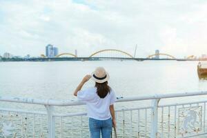 mujer viajero visitando en da nang ciudad. turista Turismo el río ver con continuar puente. punto de referencia y popular para turista atracción. Vietnam y Sureste Asia viaje concepto foto