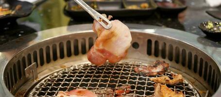 Hand Grilling meat pork on stove serve in restaurant. Japanese food and Korean BBQ traditional style photo