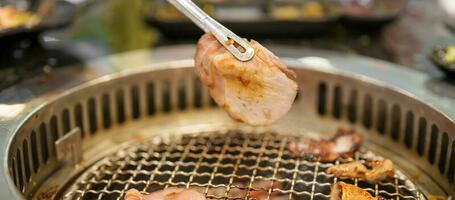 Hand Grilling meat pork on stove serve in restaurant. Japanese food and Korean BBQ traditional style photo