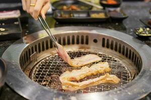 mano interrogatorio intenso carne Cerdo en estufa servir en restaurante. japonés comida y coreano barbacoa tradicional estilo foto