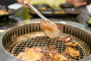 Hand Grilling meat pork on stove serve in restaurant. Japanese food and Korean BBQ traditional style photo