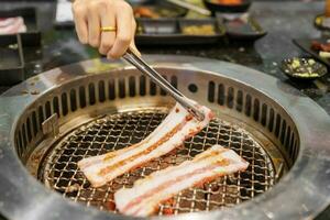 Hand Grilling meat pork on stove serve in restaurant. Japanese food and Korean BBQ traditional style photo