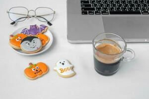 Halloween Cookies,  hot coffee and computer laptop on white background. Happy Halloween, online shopping, Hello October, fall autumn, Festive, party and holiday concept photo