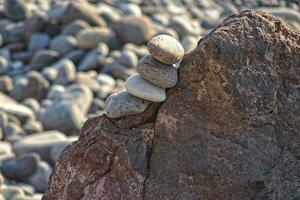 interesting tower made of stones arranged on the shore of the ocean on a warm summer's day photo