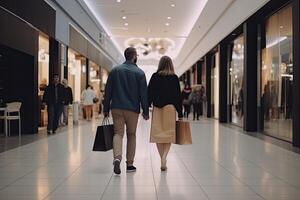 Back view of young couple walking with shopping bags in shopping mall.Husband and wife full rear view walking in a shop photo