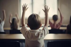 Back view of schoolboy raising hands in classroom. Back view of schoolboy raising hands in classroom. Little students full rear view raising their hands, photo