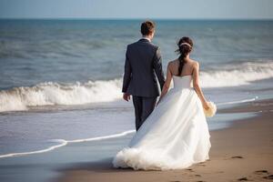 Wedding couple walking on the beach at beautiful summer day. New bride and groom full rear view walking on the beach, photo