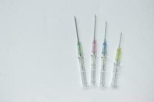 IV catheters of various sizes and colors on white background. photo