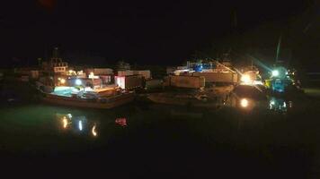 Aerial view of loading from fishing ships to cargo trucks in harbor port at night video