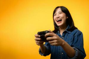 Portrait young asian woman with happy success smile wearing denim clothes holding joystick controller and playing video game. Fun and relax hobby entertainment lifestyle concept. photo