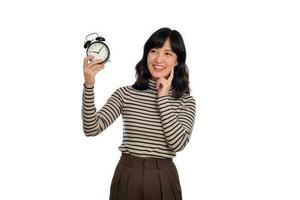 retrato de pensando joven asiático mujer con suéter camisa participación alarma reloj aislado en blanco antecedentes foto