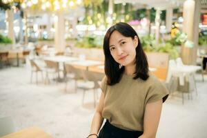 Smiling beautiful asian woman standing in cafeteria at shopping mall. photo