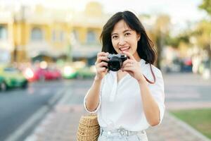 Portrait beautiful asian woman traveler with camera explore street on summer vacation in Bangkok, Thailand photo